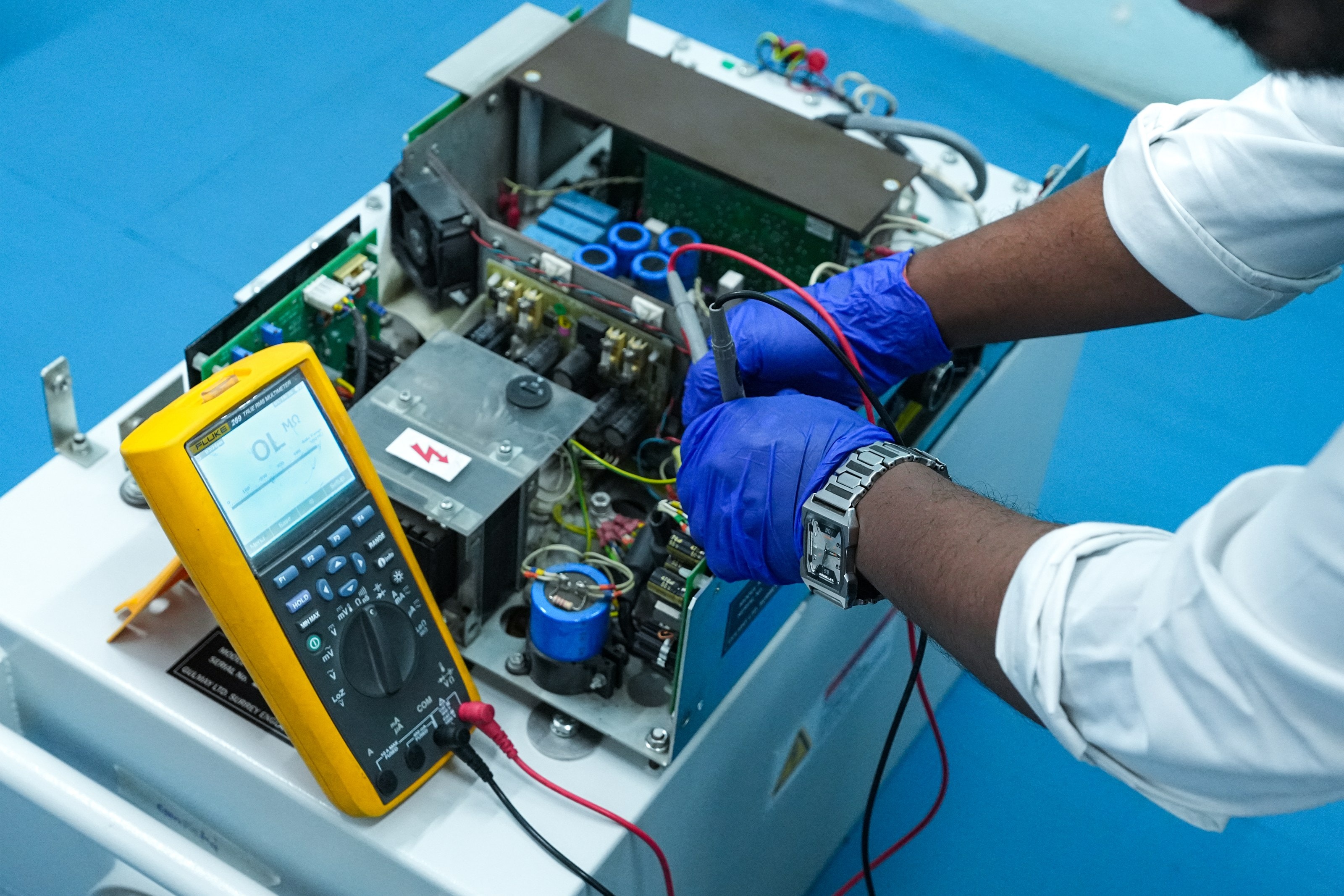 An MQS engineer testing a system's control electronics with a digital multimeter